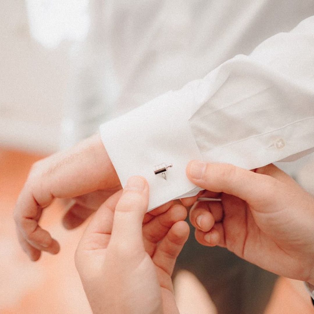 Boutons de manchette Mon Petit Poids enfilés au poignet du marié par son témoin 