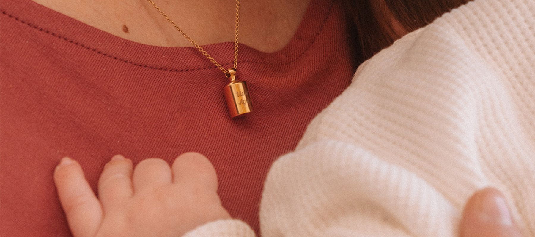 Collier personnalisé en plaqué or jaune pour la fête des mères porté par une maman avec son bébé