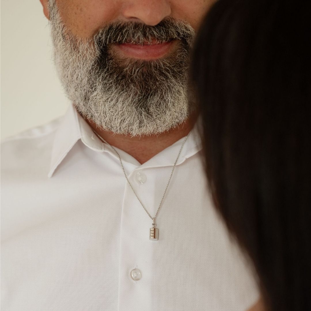 Collier Mon Petit Poids homme argenté rhodié, porté par un homme sur une chemise blanche 