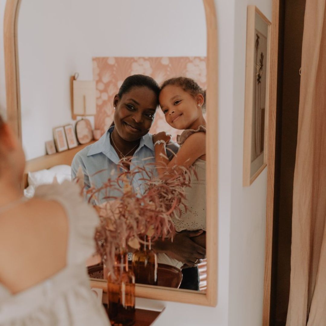 Photo d'une maman et de sa fille, tout sourire, dans un miroir