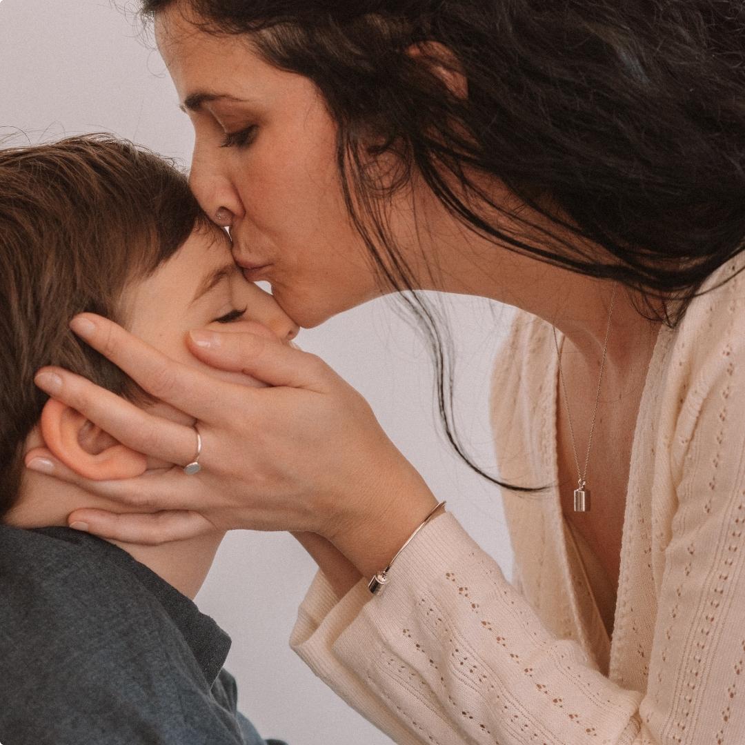 Bague Madeleine perlé argenté rhodié porté par une maman faisant un bisou sur le front de son fils.