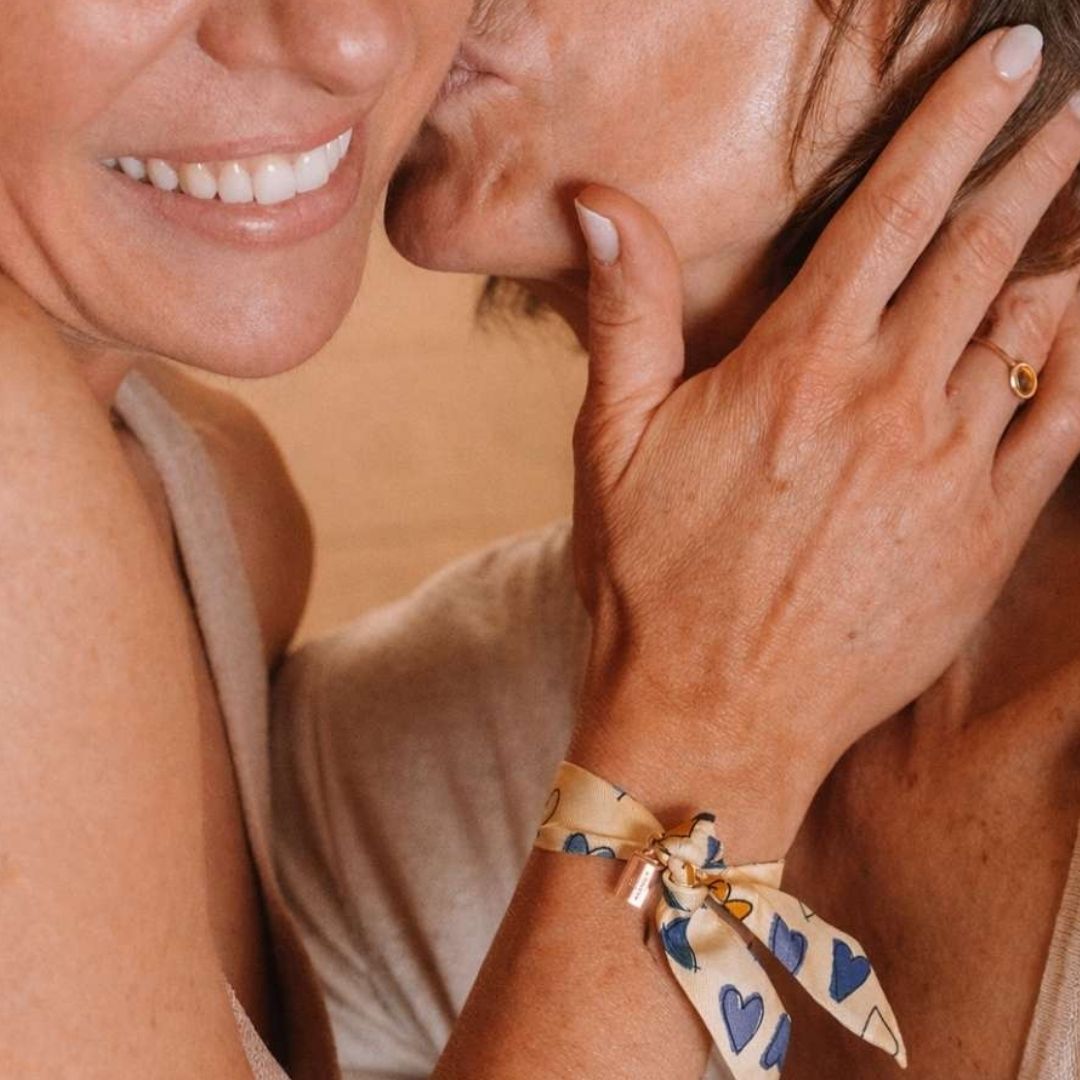 Bracelet Les Mots Bleus porté par une femme qui caresse la tête de sa maman, elle lui fais un bisous en retour.