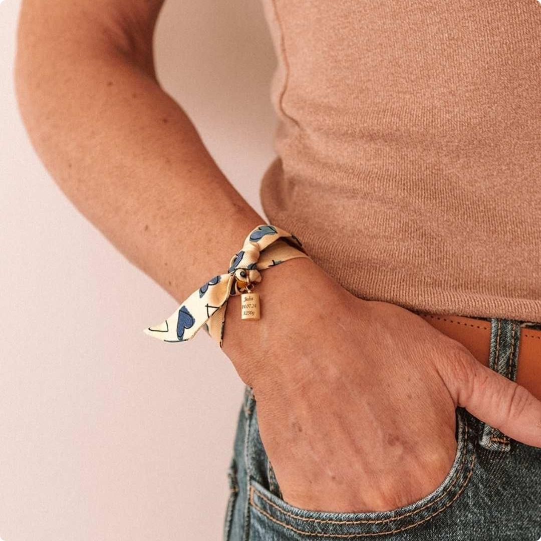 Bracelet Les Mots Bleus plaqué or jaune porté par une femme avec la main dans sa poche. 