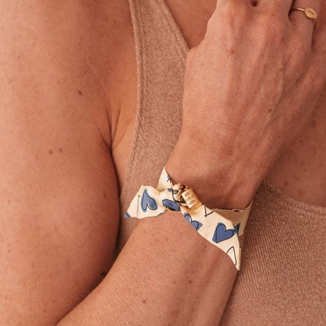 Bracelet Les Mots Bleus plaqué or jaune porté par une femme avec un débardeur couleur beige.