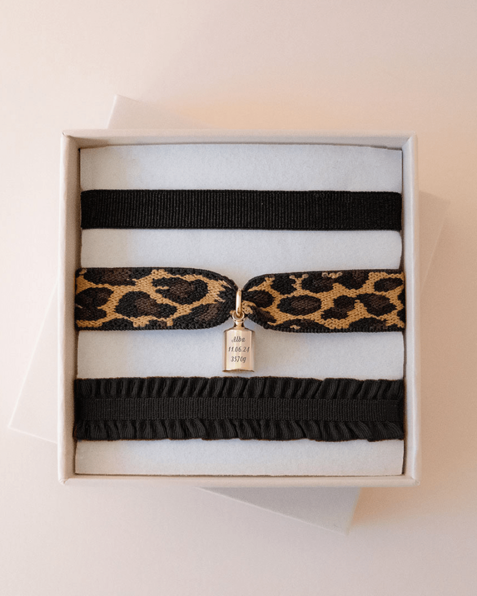 Coffret bracelets Mon Petit Poids léopard plaqué or jaune avec un ruban fin noir, un ruban léopard avec le poids accroché, un ruban froufrou noir