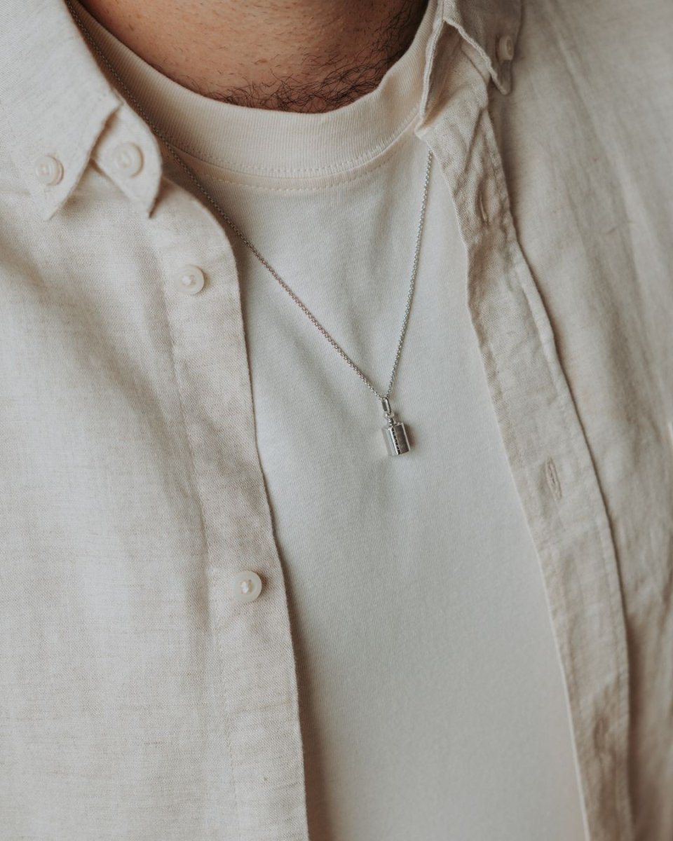 Collier Mon Petit Poids homme argenté rhodié sur un homme portant  un t-shirt blanc et une chemise écru