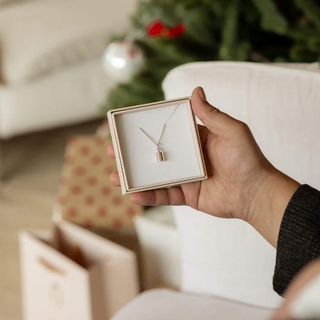collier mon petit poids homme dans son écrin, tenu dans la main d'un homme