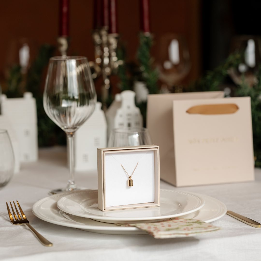 Collier Mon petit poids en plaqué or jaune dans son écrin, posé dans une assiette