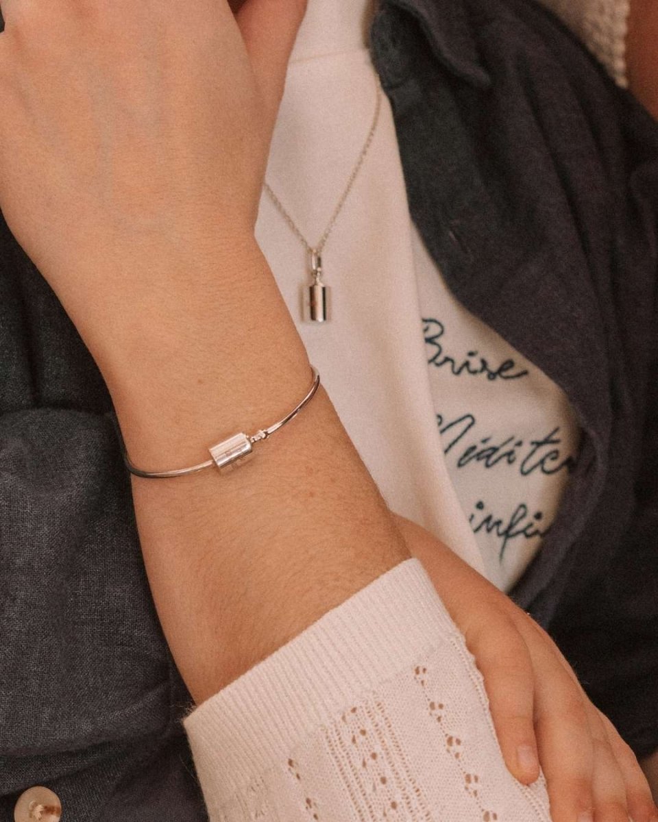 Enfant dans les bras de sa maman portant le jonc Mon Petit Poids argenté rhodié avec pendentif gravé personnalisable et collier Mon Petit Poids assorti