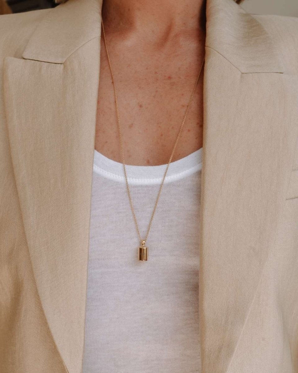 Femme portant un sautoir personnalisé Mon Petit Poids en plaqué or jaune avec pendentif cylindrique gravé sur chaîne longue dorée